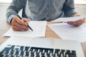 Persona revisando documentos apoyados en una mesa de trabajo
