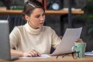 Persona concentrada examinando varios papeles sobre un escritorio
